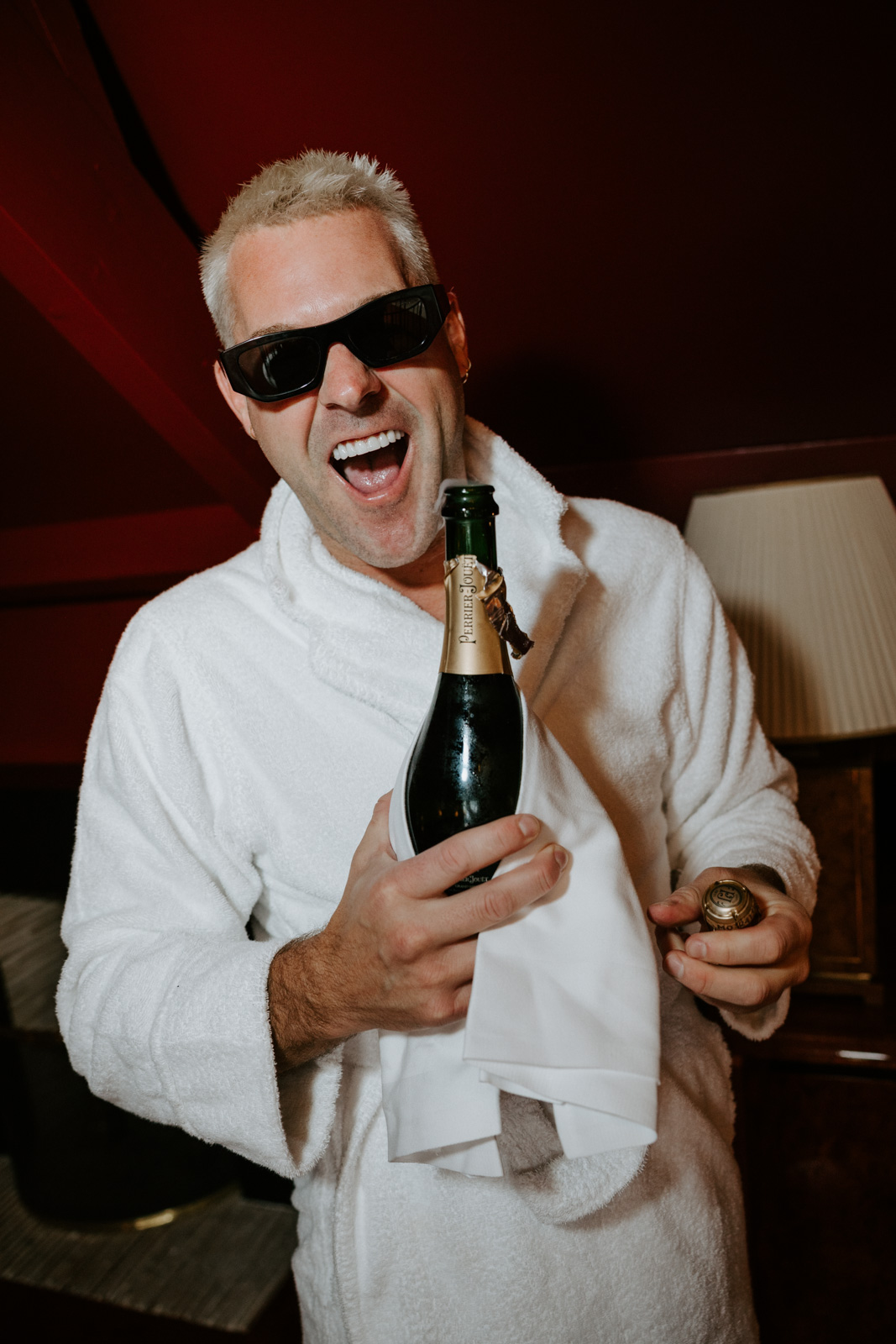 The grooms are getting ready for their ceremony at Hotel Particulier Montmartre, Paris, popping a bottle of Champagne