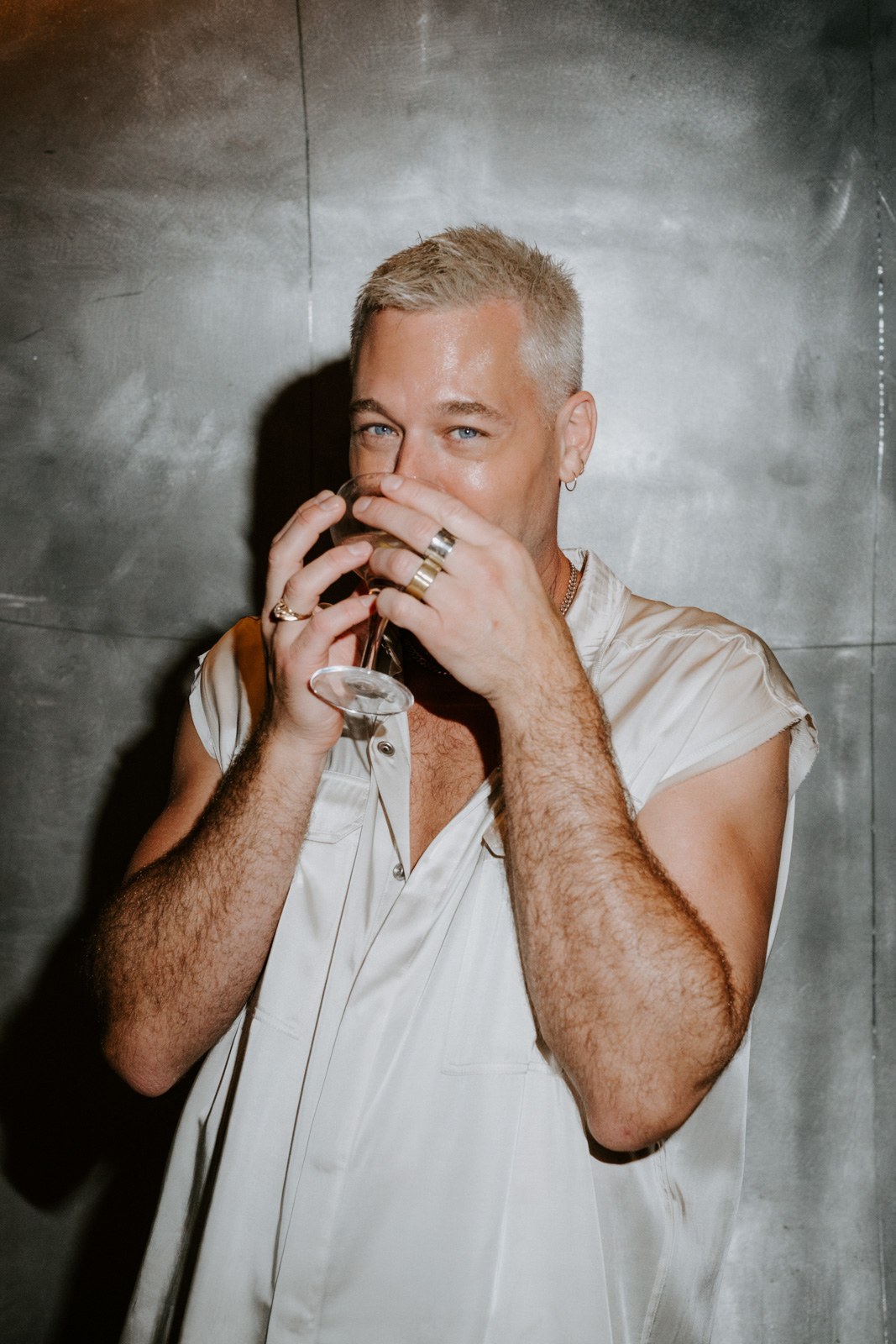 portrait of the groom laughing and drinking at his wedding's welcome dinner at Le Georges, on the rooftop of Pompidou Centre in Paris